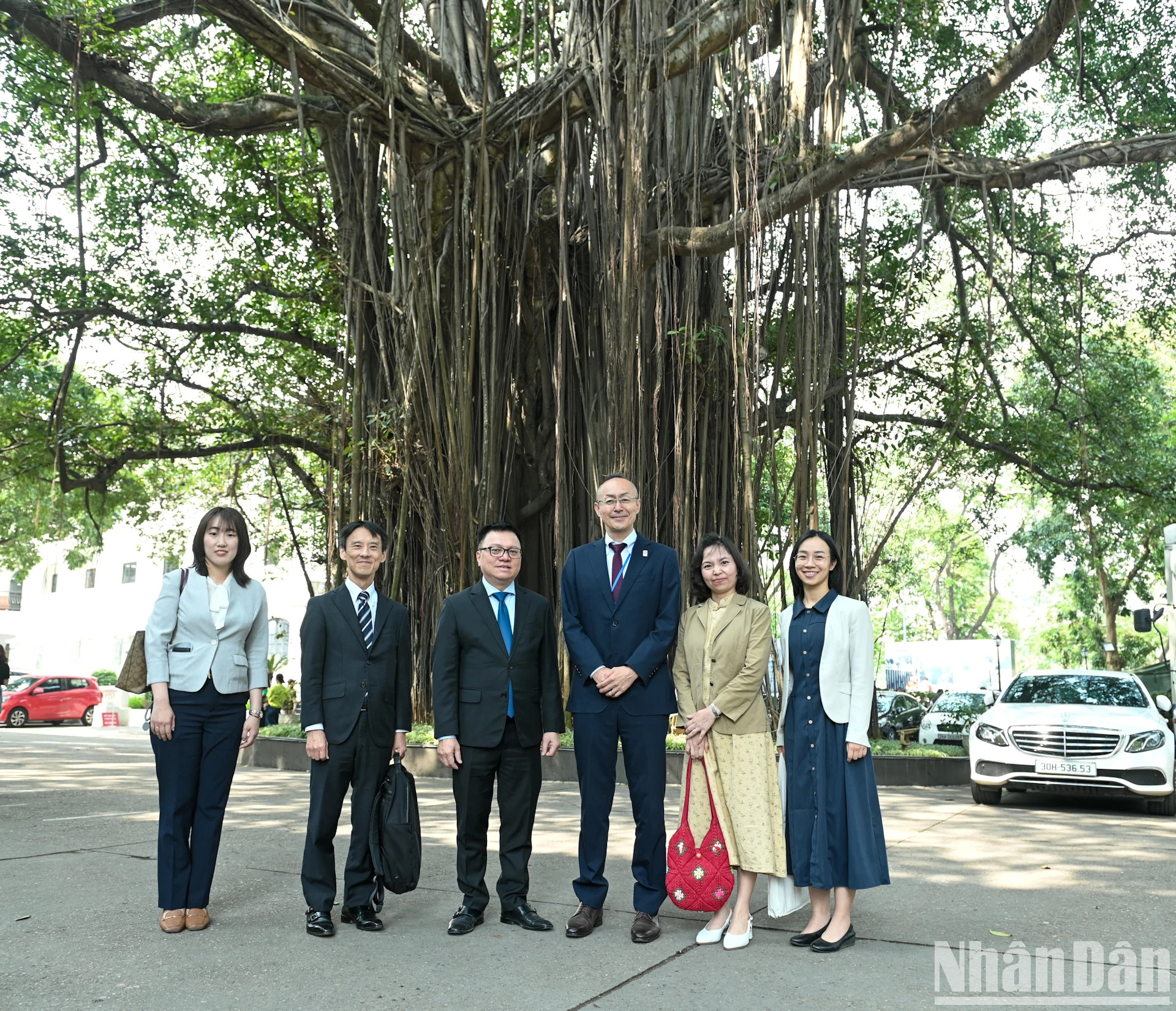 《人民报》社总编辑黎国明与日本国际协力机构代表团成员在《人民报》社院内500年古榕树下合影留念。