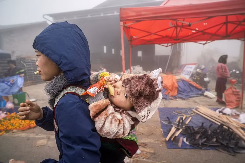 母亲背着孩子赶上河江省同文县庯告集市。