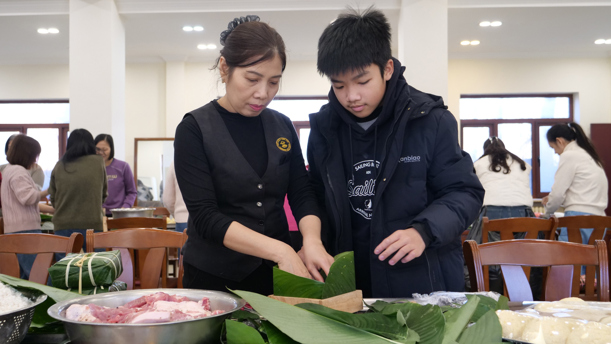 指导年轻人包粽子。