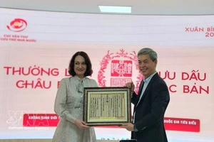 越南国家文书与档案局局长邓青松向俄罗斯驻越大使夫人埃琳娜·贝兹德特科赠送一幅越南国号的木刻版画。（图片来源：越通社）