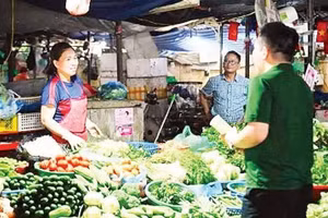 河内市同沙市场的个体经营者在摊位前接受越南盛旺股份商业银行职员指导，开设个体工商户账户。