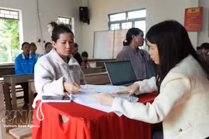 林同省达能乡公务员在新下村流动公共行政服务点指导民众办理司法、户籍手续。（图片来源：越通社）