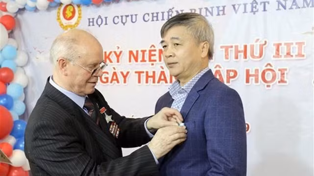 俄罗斯老兵协会主席科列斯尼克向越共驻俄罗斯国外事务管理机关党委副书记、越南老兵吴国泰授予纪念章。