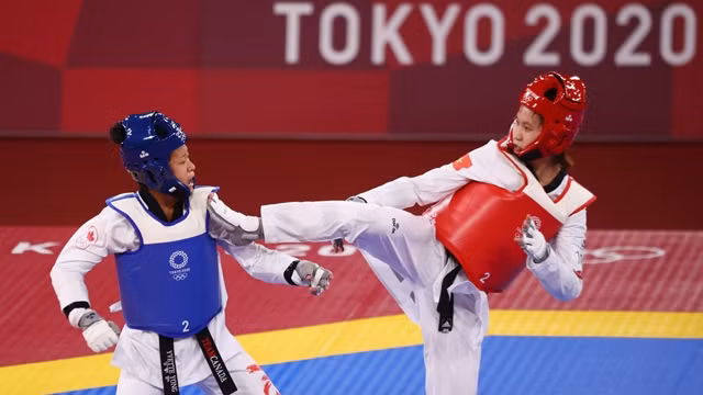 越南跆拳道选手张氏金琁（红护具）在比赛中脚踢进攻。