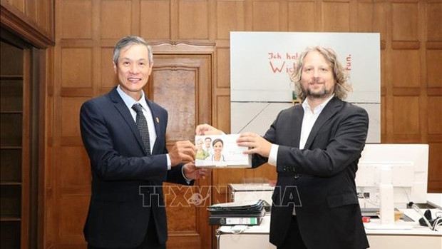 柏林经济部国务秘书克里斯蒂安·瑞克茨代表柏林市政府向越南驻德大使阮明宇象征性转交3万套快速检测试剂盒。