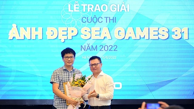 《人民报》社总编辑黎国明向获得一等奖的摄影师张英德颁奖。