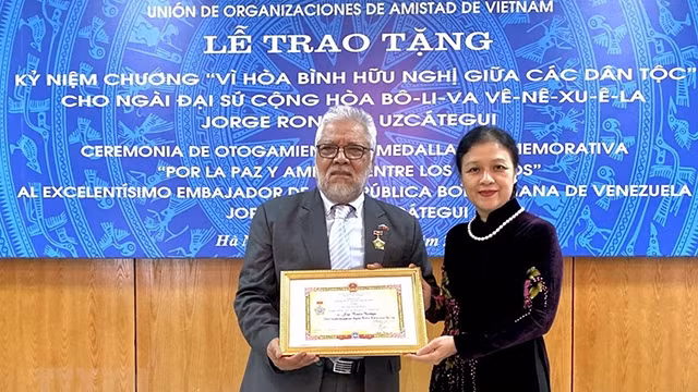阮芳娥大使向豪尔赫·隆东·乌斯卡特吉大使授予“致力于各民族和平友谊”纪念章。（图片来源：越通社）