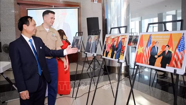 广治省人民委员会主席武文兴和美国驻越南海军陆战武官查克·凯西观看图片展。