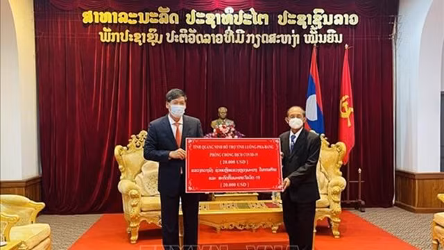 阮登雄总领事向老挝琅勃拉邦省省长坎汗·占塔维苏克转交援助资金。