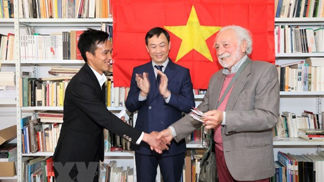越意友好协会威内托大区分会主席达西向越南大学生代表交接在威尼斯越南文化屋。（图片来源：越通社）