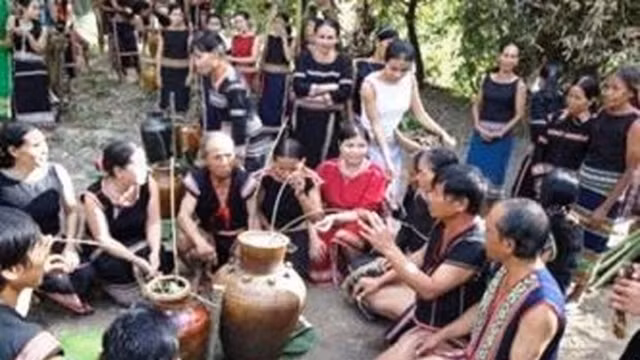 村民围坐在酒罐边畅饮。