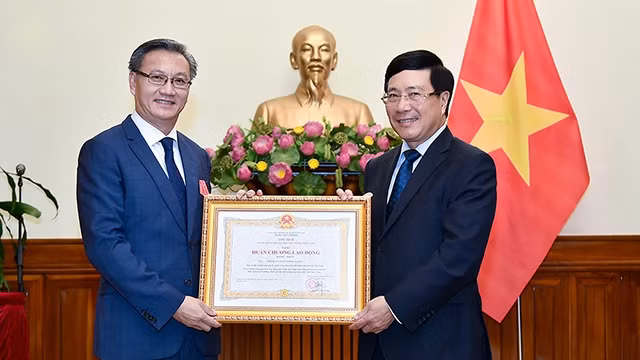 政府副总理兼外交部长范平明向老挝驻越南大使通沙万•丰威汉授予一级劳动勋章。（图片来源：VGP）