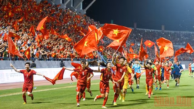 主裁判吹响了终场比赛的哨音，越南女球员手拿着国旗在体育场上庆祝胜利。