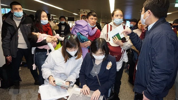 越南驻波兰大使馆干部为侨胞们办理登机手续。（图片来源：越通社）
