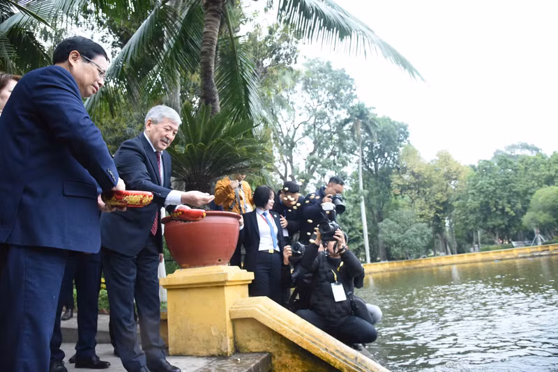 范明正总理和阿德尔别克·卡西马利耶夫总理参观高脚屋正前方的胡伯伯鱼塘并喂鱼。