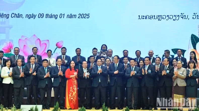 越南政府总理范明正与老挝总理宋赛·西潘敦和两国企业代表合影。（青江 摄）