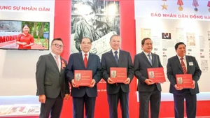越共中央总书记苏林与党和国家领导同志及代表们在《人民报》社展区获赠《胡志明主席在〈人民报〉上发表的关于文化与新闻的文章选编》一书。