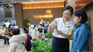 Vietcombank银行业务人员引导客户使用银行应用程序上的生物识别功能。（图片来源：《人民军队报》）