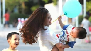 周末，一位母亲和孩子玩耍，脸上洋溢着幸福的笑容。