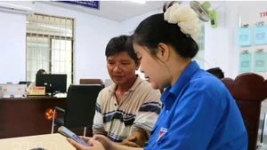 青年向河静省当地居民介绍并指导使用“i-HaTinh”数字公民应用程序的操作流程。（图片来源：越通社）