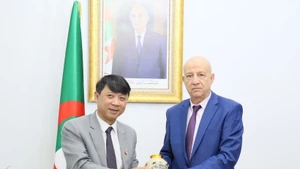 越南《共产主义杂志》社副总编辑阮玉河副教授向阿民族解放阵线党总书记阿卜杜勒克里姆·本穆巴拉克赠送纪念品。(图片来源:越通社)