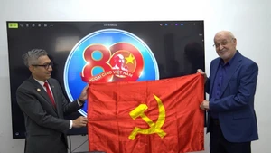 越南驻以色列大使李德忠向以色列共产党政治局委员、哈达什阵线主席伊萨姆·马库尔赠送党旗。