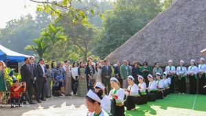 越南各民族文化旅游村的芒族同胞向游客推介本民族文化特色。