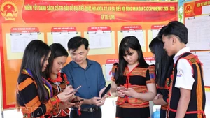 岘港市茶灵乡色当族同胞正在用手机查看有关第十六届国会及各级人民议会代表选举的视频和图表新闻，了解投票流程。