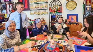 陈重义博士与文莱达鲁萨兰国国立大学学生共同体验越南与文莱传统图案装饰活动。（图片来源：越南驻文莱大使馆提供）