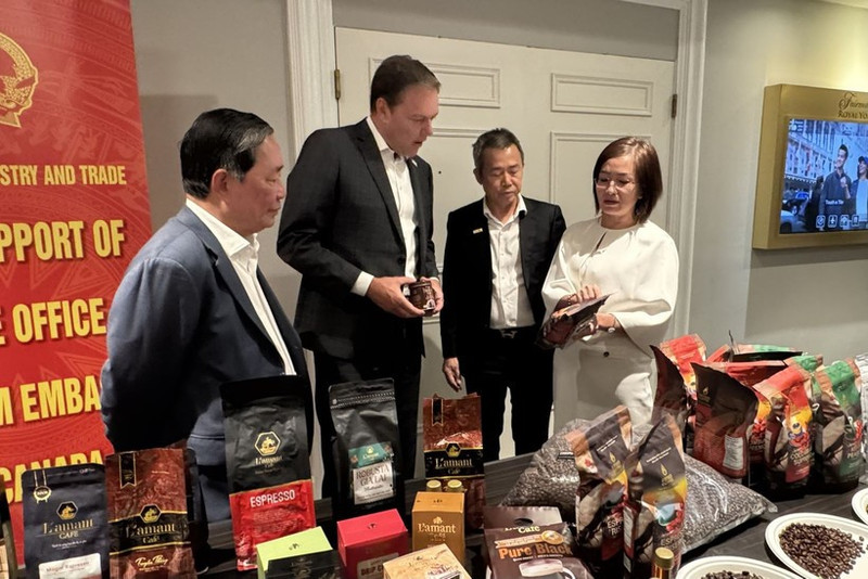 越南驻加拿大商务参赞陈秋琼向加拿大咖啡协会主席罗伯特·卡特介绍越南咖啡。（图片来源：越通社）