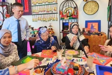 陈重义博士与文莱达鲁萨兰国国立大学学生共同体验越南与文莱传统图案装饰活动。（图片来源：越南驻文莱大使馆提供）