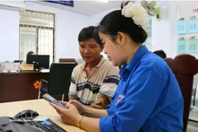 青年向河静省当地居民介绍并指导使用“i-HaTinh”数字公民应用程序的操作流程。（图片来源：越通社）