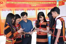 岘港市茶灵乡色当族同胞正在用手机查看有关第十六届国会及各级人民议会代表选举的视频和图表新闻，了解投票流程。