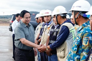 范明正总理与富国国际机场项目一线工作人员亲切握手。（图片来源：政府门户网）