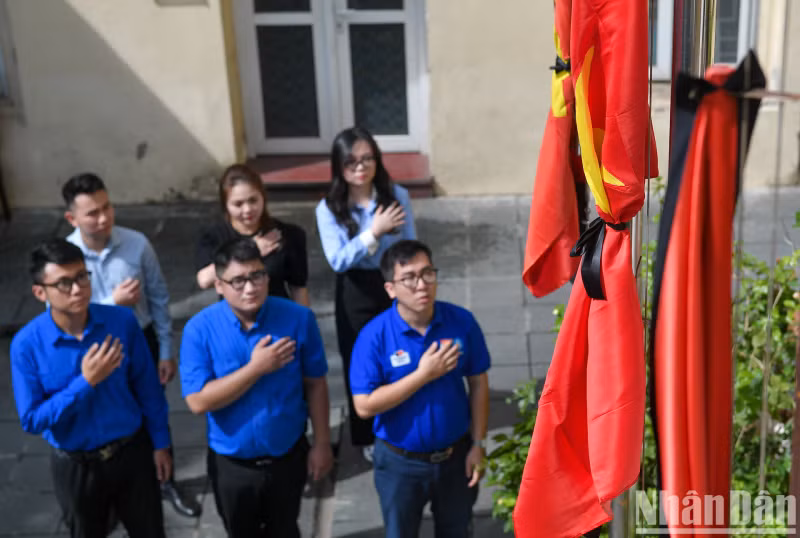 河内市团市委干部、团员站在旗帜前缅怀阮富仲总书记。
