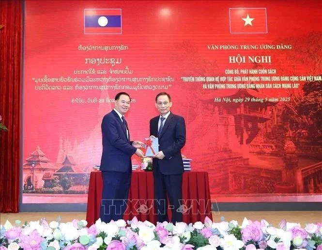 黎怀忠同志向通沙立·蒙诺梅同志赠送《越共中央办公厅和老挝人民革命党中央办公厅合作关系传统》一书。（图片来源：越通社）