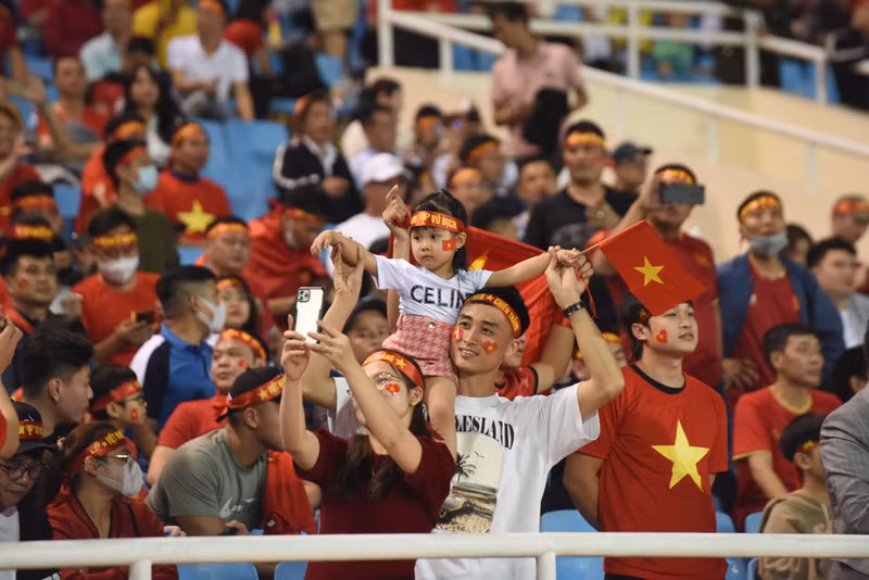 小朋友跟父母在体育场上一起跟父母看球赛。