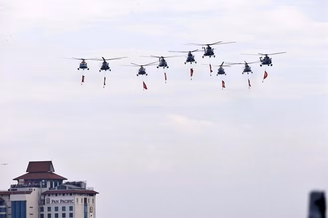 人民空军直升机编队悬挂党旗与国旗飞越河内上空。