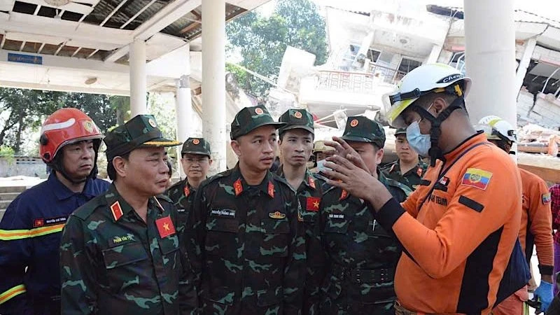 越南军队救援队队长范文巳少将与缅甸内政部消防局代表就专业技术、任务内容、搜救方法及组织实施方式进行了简要交流，并达成一致意见。（图片来源：《人民军队报》— 缅甸现场报道）