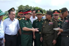 越南国防部副部长黄春战中将（左三）与柬埔寨皇家陆军副总司令伊萨拉将军（右二）讨论在柬埔寨柴桢省柴桢县建设桑索瓦纳小学友谊项目计划。（图片来源：越通社）