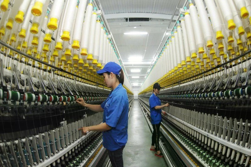 3·8纺织公司工人正在操作纱线生产线。（陈海 摄）