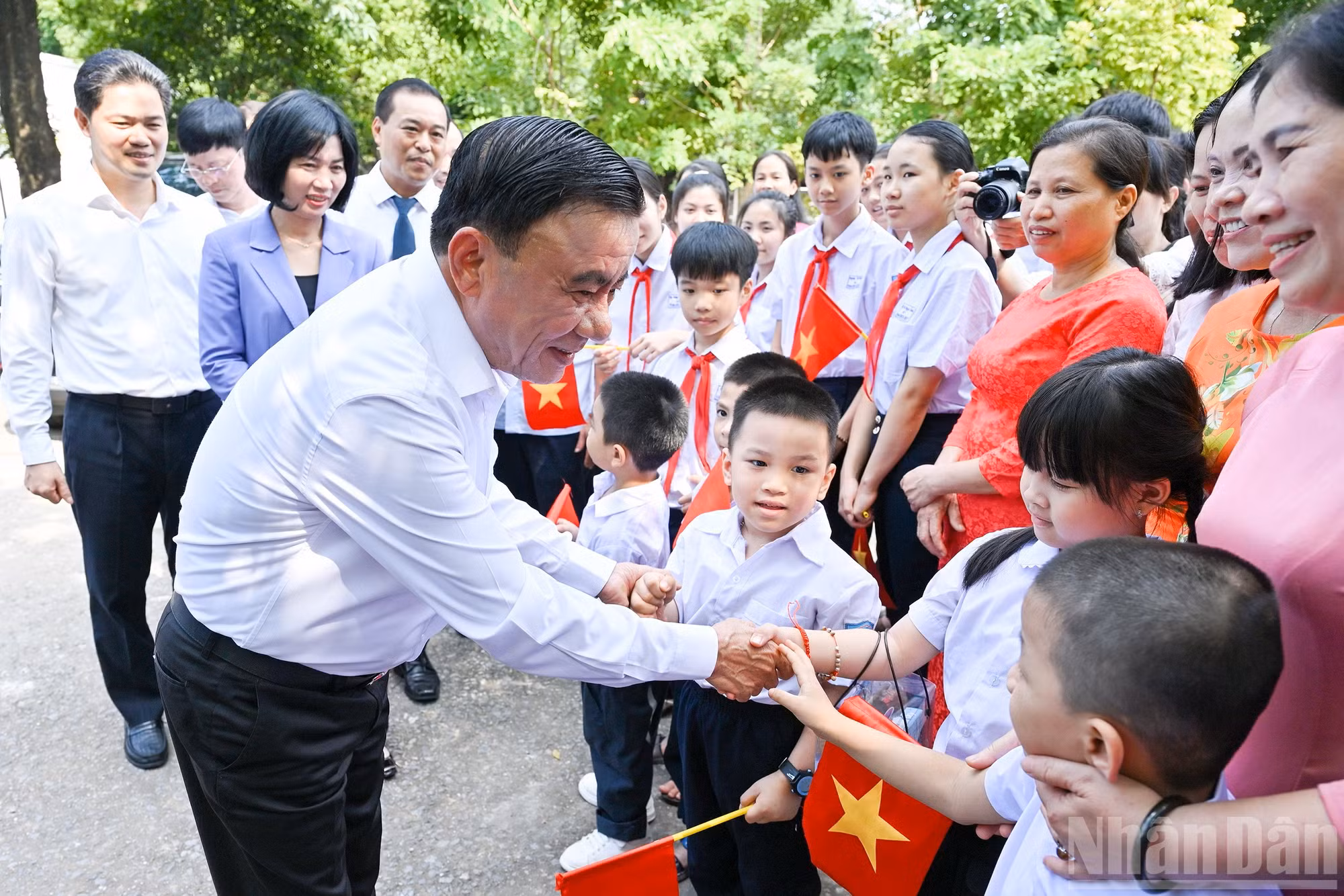 中央书记处常务书记陈锦秀与少年儿童握手。