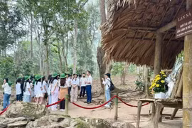 导游向游客介绍宣光省的诺娜棚屋遗迹。