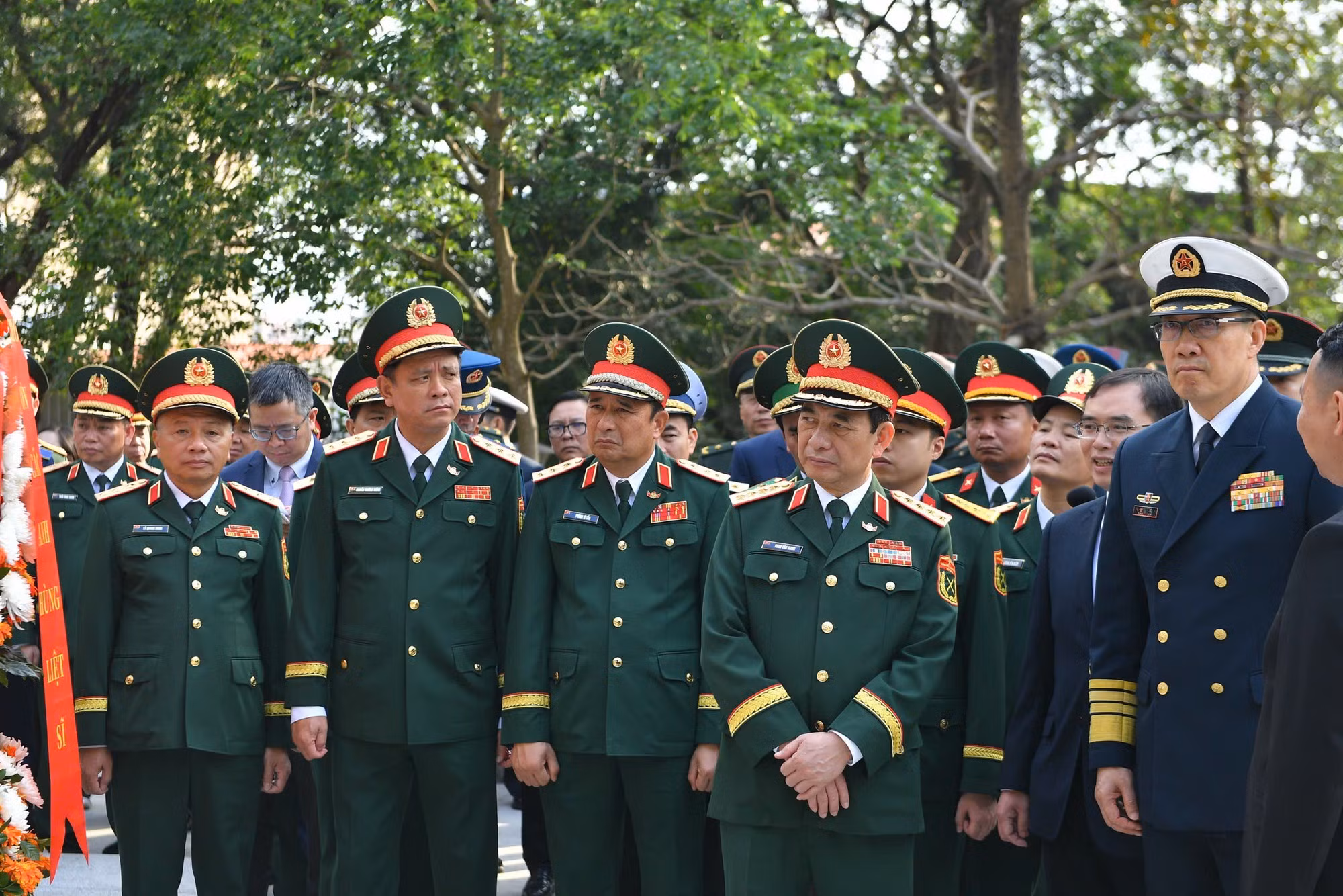 潘文江大将与董军上将以及两国各位代表倾听关于越中人民革命烈士纪念碑的介绍。