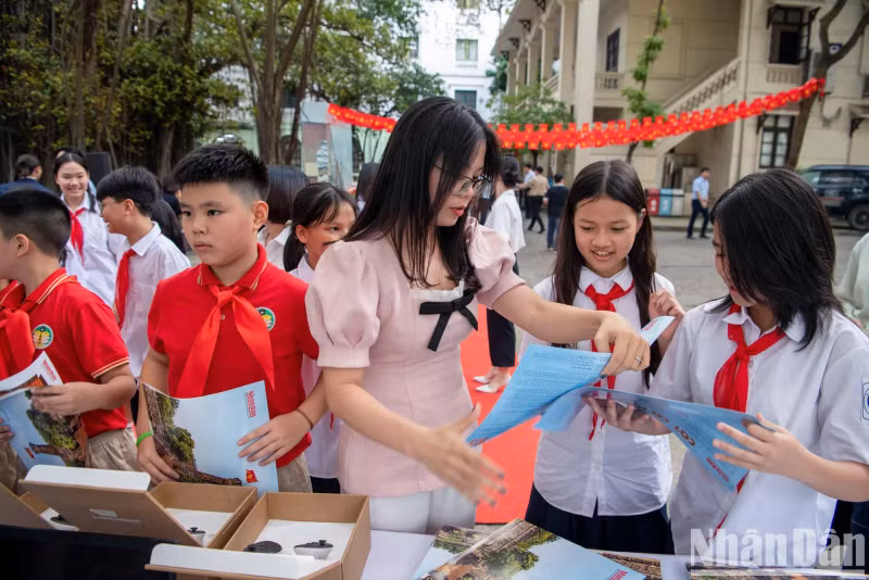 组委会代表向学生们发放《人民报》副刊，读者可以切割并组装成河内旗台的模型。