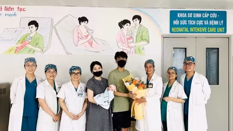 岘港妇产儿科医院医护人员向即将出院的一家三口赠送鲜花表示祝贺。