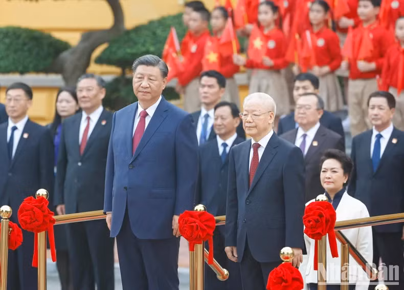 越共中央总书记阮富仲和中共中央总书记、中国国家主席习近平登上检阅台，军乐奏响两国国歌。