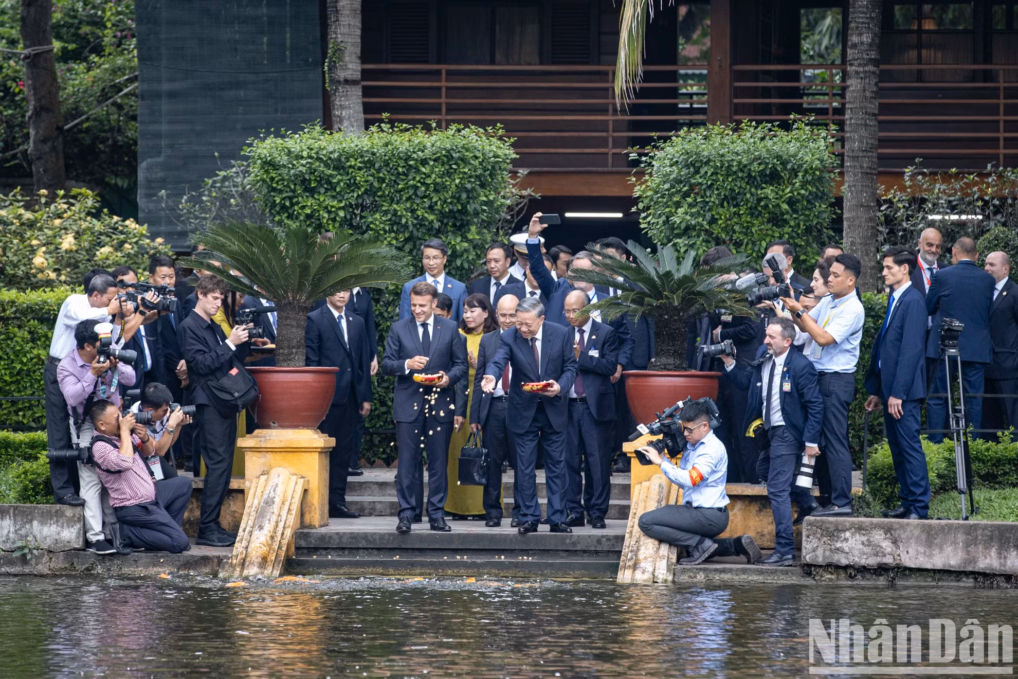 越共中央总书记苏林向法国总统埃马纽埃尔·马克龙在胡伯伯鱼池喂鱼。
