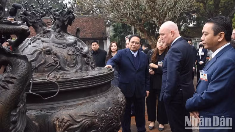 越南政府总理范明正向新西兰总理卢克森介绍文庙-国子监的文物。