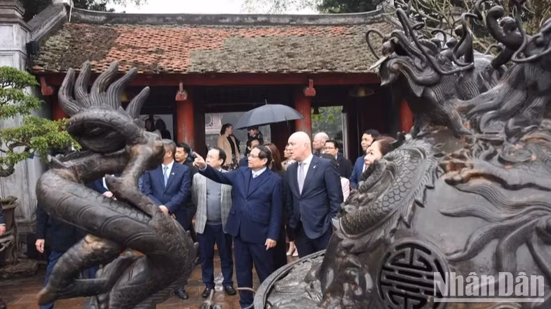 越南政府总理范明正向新西兰总理卢克森介绍文庙-国子监的文物。